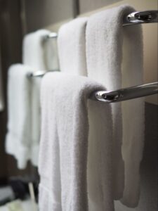 Four white towels hang neatly on a heated towel rack.