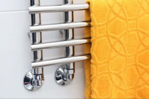 A yellow towel is neatly folded over a silver heated towel rack.