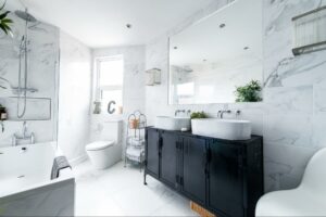 A clean, modern bathroom with black cabinets, marbled walls, and a large bathtub.