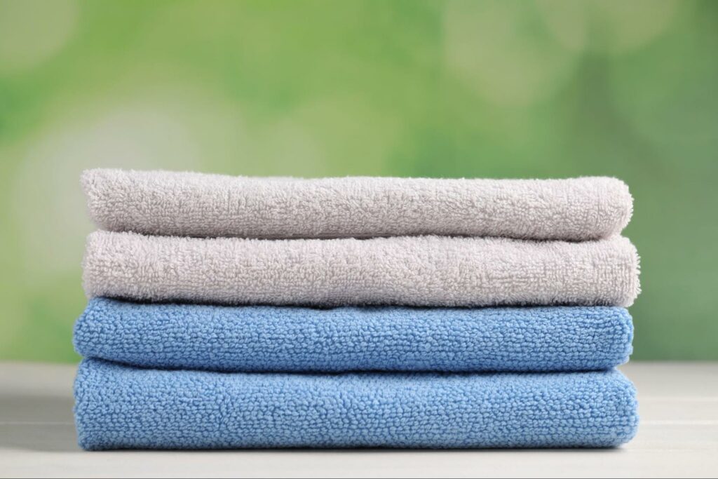A stack of four oversized bath towels, neatly folded, with two blue and two gray towels.