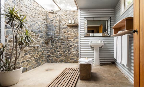 A modern cabin bathroom decorated with a natural stone wall and contemporary elements.
