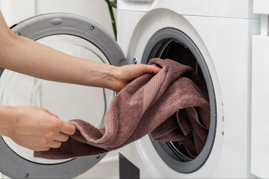 Pulling a clean towel from a dryer to get rid of the musty smell.